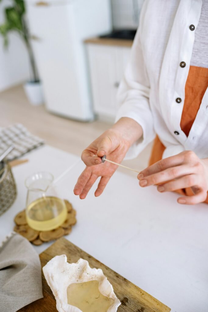 Close-up of a woman crafting a handmade candle with a natural conch shell mold.